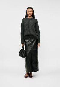 Γκρίζος πλεκτός σκούφος με φαρδιά μανίκια, συνδυασμένος με μια μαύρη δερμάτινη μιντι φούστα. Τα αξεσουάρ περιλαμβάνουν μια μαύρη τσάντα χειρός και βουργουνδί τακούνια.