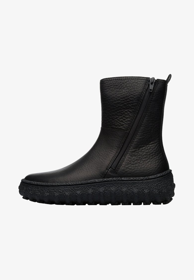 Bottine en cuir noir texturé avec semelle épaisse et robuste et fermeture éclair latérale sur fond blanc.