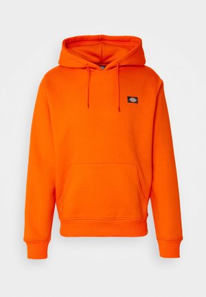 Felpa arancione brillante realizzata in tessuto morbido. Presenta una tasca a marsupio frontale, cappuccio regolabile con cordoncino e un piccolo patch con logo sul petto.