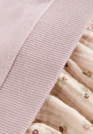 Tissu côtelé rose pâle à côté d'un textile crème froncé comportant de petits motifs floraux aux couleurs douces. Texture douce, design superposé.