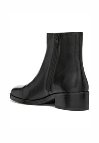 Bottine en cuir noir avec une texture lisse, fermeture éclair latérale, bout arrondi et un petit talon carré, mettant en avant un design épuré sans embellissements.