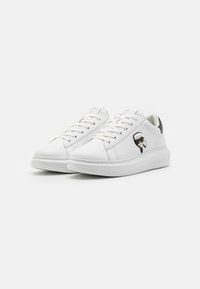 Sneaker bianche in pelle con punta rotonda, cuciture tono su tono e un accento nero sul tallone, caratterizzate da un logo di un personaggio dei cartoni animati sul lato.