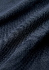 Donker marineblauwe stof met een getextureerd oppervlak, met zichtbare geweven patronen en subtiele ribbels, die een gladde, zachte uitstraling toont.