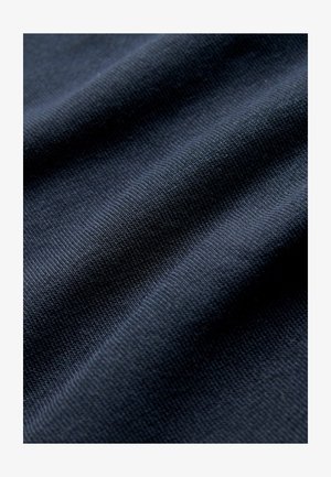 Dunkel marineblauer Stoff mit strukturierter Oberfläche, sichtbar gewebten Mustern und subtilen Rippen, der ein glattes, weiches Erscheinungsbild zeigt.