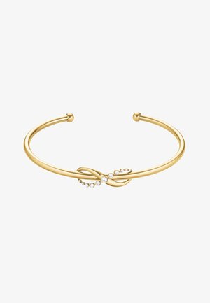 Gouden open armband met een infinity knoop als middelpunt, versierd met kleine ronde heldere kristallen op een witte achtergrond.