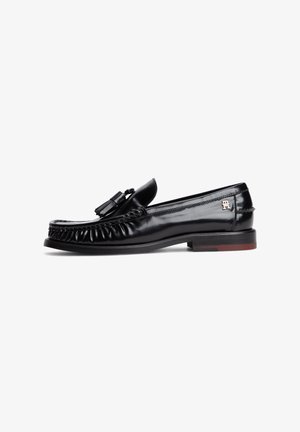 Schwarzer Ledertasselloafer für Herren mit niedrigem Absatz, seitlichem Logo und detaillierter Naht vorne und an den Seiten.