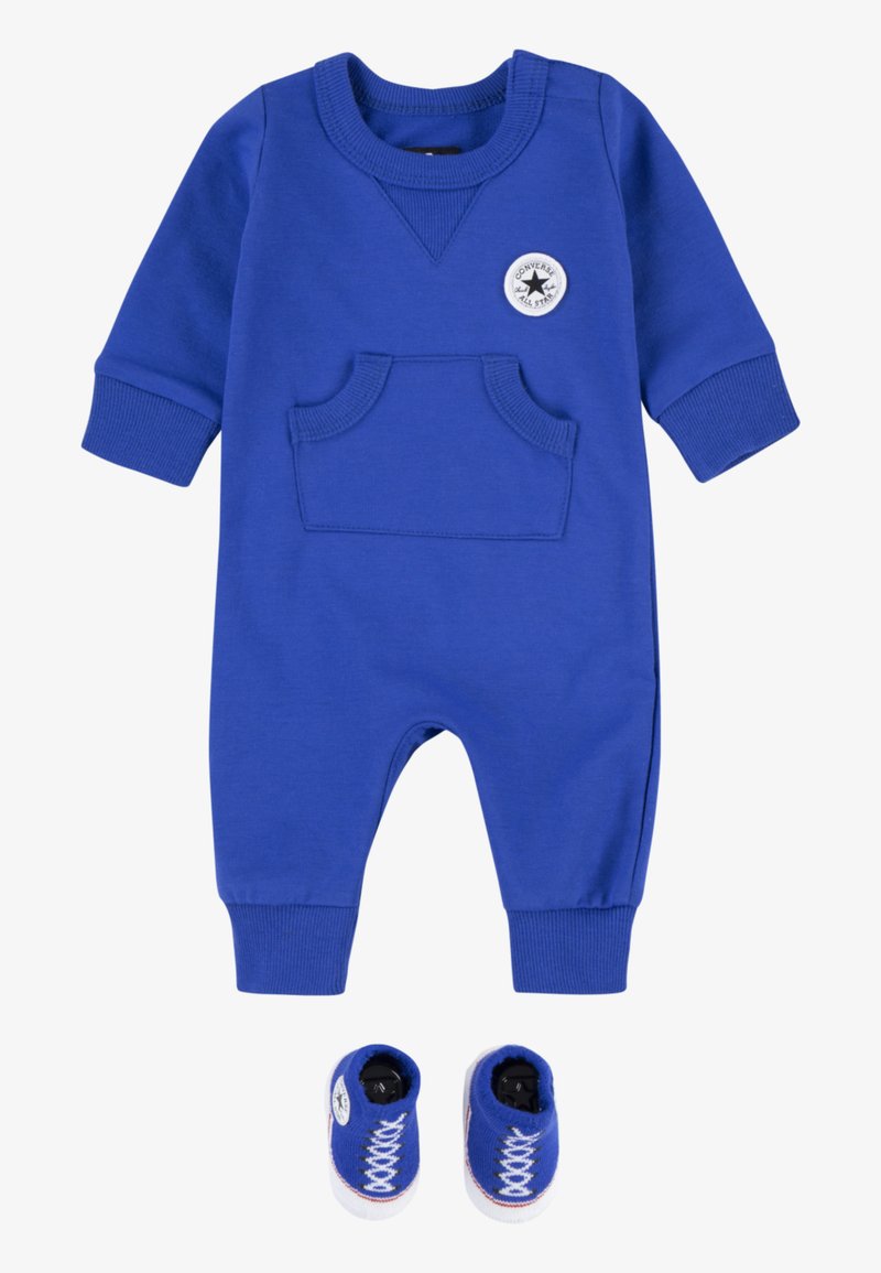Macacão para bebé azul com um bolso, punhos canelados e decote redondo; inclui botinhas azuis combinadas que imitam sapatilhas com atacadores brancos.