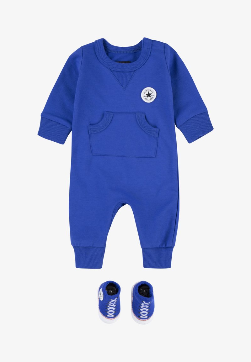 Modra dojenčkova obleka z žepom, reberčastimi manšetami in okroglim ovratnikom; vključuje ujemajoče se modre copatke, ki posnemajo superge z belimi vezalkami.