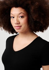 Sort ribbet v-hals top med korte ærmer, der har en tætsiddende pasform. Stoffet ser blødt ud med en diskret tekstur. Velegnet til hverdag.