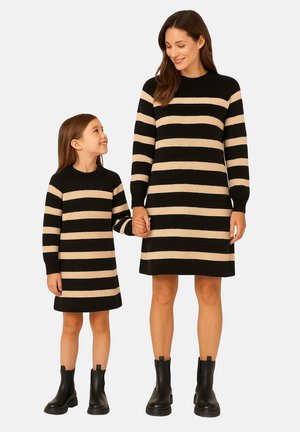 Gestreifte Strickkleider in Schwarz und Beige, mit langen Ärmeln und rundem Halsausschnitt. Sowohl Erwachsenen- als auch Kindergrößen sind zu sehen, beide tragen schwarze Knöchelstiefel.