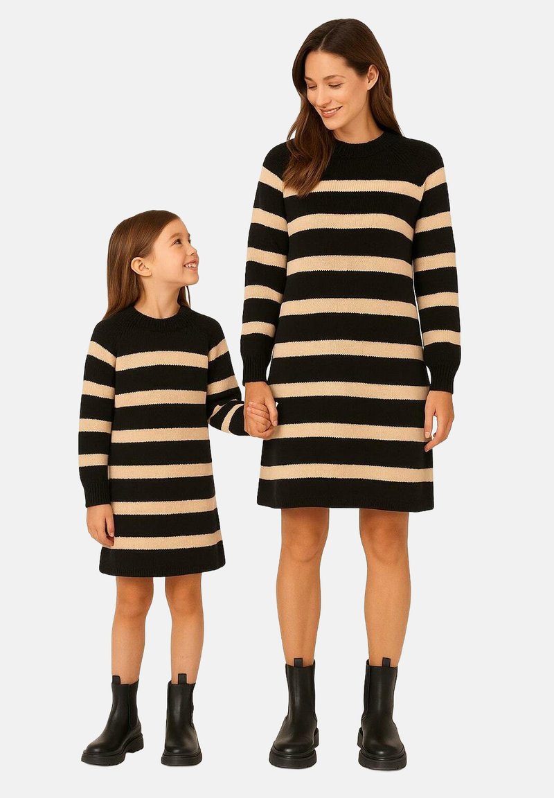 Gestreifte Strickkleider in Schwarz und Beige, mit langen Ärmeln und rundem Halsausschnitt. Sowohl Erwachsenen- als auch Kindergrößen sind zu sehen, beide tragen schwarze Knöchelstiefel.