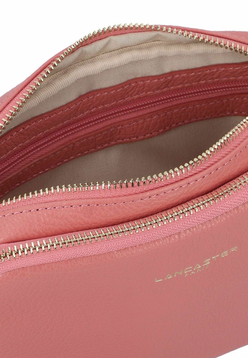 Portefeuille en cuir rose avec des zips en or, comprenant plusieurs compartiments et un intérieur texturé. Logo embossé à l'extérieur.