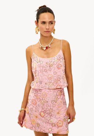 Roze kraaltop met bloemensoftware, gecombineerd met een bijpassende minirok. Bevat delicate bandjes en ingewikkelde kraaldetails.