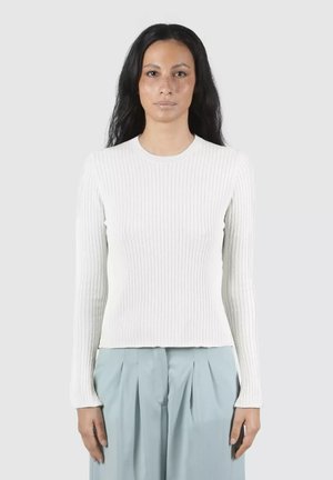 Maglietta a maniche lunghe bianca a coste con collo rotondo, design aderente e motivo testurizzato. Indossata con pantaloni plissettati blu chiaro.
