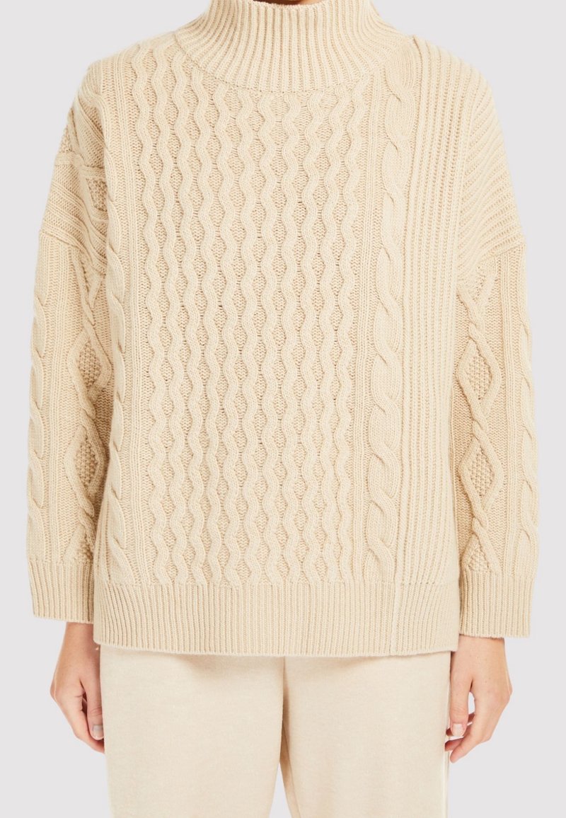 Beige neulepaita korkealla kauluksella, jossa on teksturoitu palmikkokuvio ja resorit hihansuissa ja helmassa. Pehmeä, mukava ja väljä istuvuus.