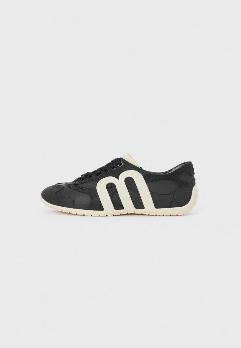 Black athletic shoe with a smooth fabric upper, featuring a bold white logo on the side, textured accents, and a white rubber sole.
