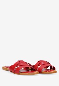 Sandales plates rouges avec des brides entrelacées, en cuir souple, à semelle plate et bord de semelle en bois naturel. Aucun ornement ni motif.