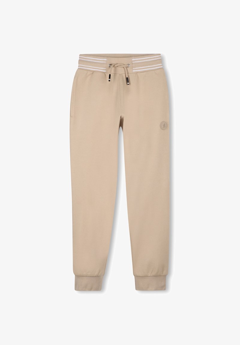 Pantalon de survêtement beige avec taille à cordon, bande élastique rayée et jambes fuselées. Présente un petit logo sur la cuisse gauche. Texture de tissu douce.