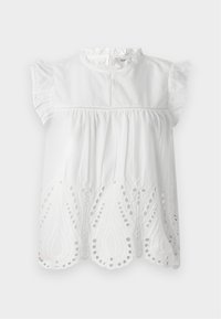 Blouse en coton blanc avec des manches à volants, un col haut et des détails en broderie œillet au bas dans un motif paisley.