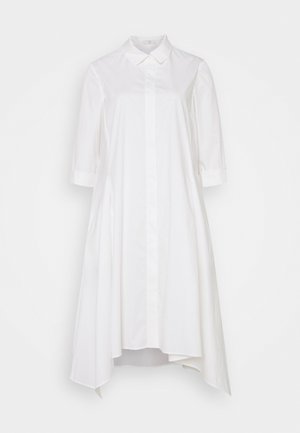 Biała sukienka na guziki z rękawami do łokcia, ostro zakończonym kołnierzem i asymetrycznym dołem, wisząca na białym tle.