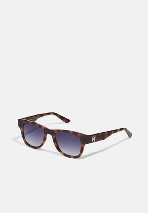 Occhiali da sole tartarugati con un design massiccio, lenti scure sfumate e logo decorativo sull'asta. Realizzati in materiale plastico resistente.