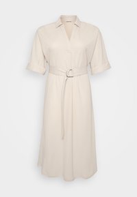 Beige shirt dress with a collar and rolled-up sleeves, featuring a waist belt with a circular buckle, hanging on a plain background.