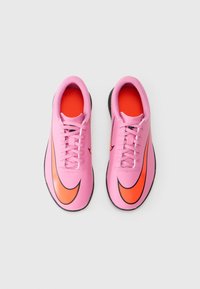 Et par rosa og oransje Nike sportssko med snører, sett fra oven på en hvit bakgrunn.
