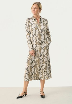 Robe chemise à manches longues avec un motif imprimé serpent, dotée d'un col, d'une fermeture à boutons sur le devant et de poches latérales. Les couleurs incluent le beige, le noir et le brun.