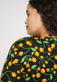 Tecido preto com um vibrante padrão de cerejas em laranja e verde, com linhas curvadas e folhas, destacando um design de padrão divertido.