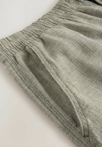 Lysegrå shorts med elastisk talje, udstyret med et tekstureret herringbone-mønster, der har tre lommer og syede detaljer langs sømmene.