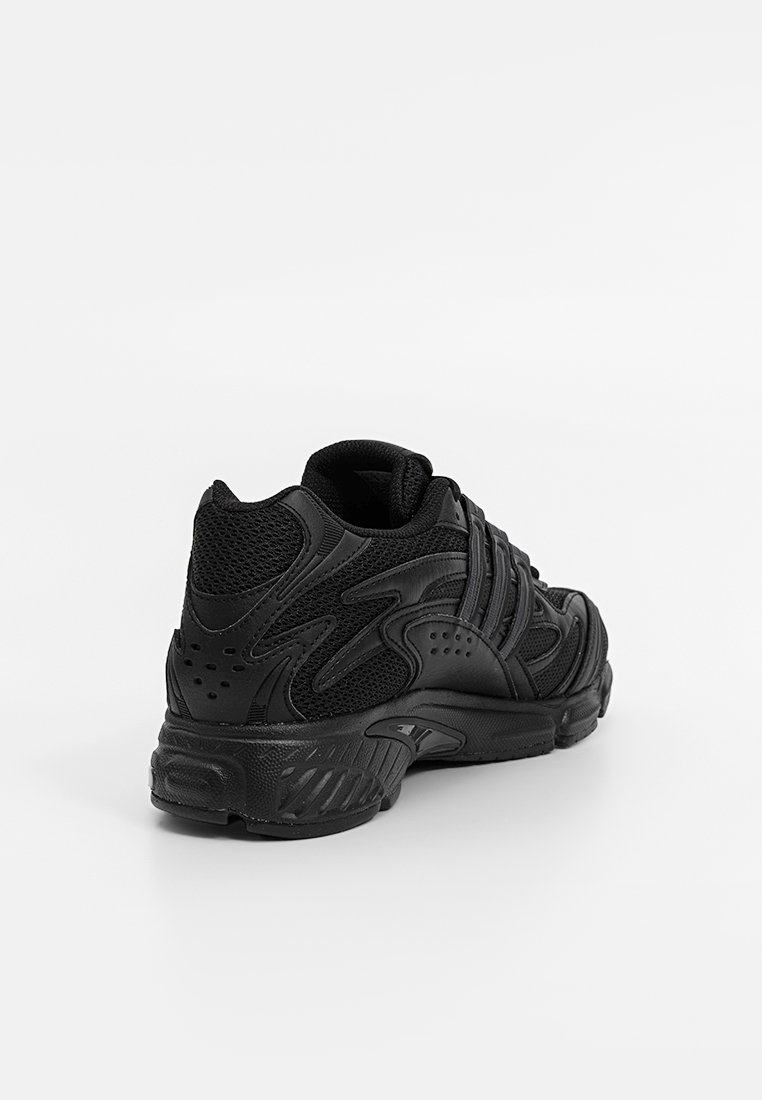 Zapatillas deportivas negras con parte superior de malla, superposiciones texturizadas, cuello acolchado y suela de goma con patrones de relieve distintivos.