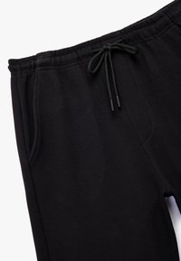Schwarze Jogginghose aus strukturiertem Stoff, mit elastischem Bund und verstellbarem Kordelzug. Verfügt über Seitentaschen und einen lockeren Schnitt.