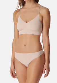 Kevyt, saumaton, vaalea beige bralette säädettävillä olkaimilla ja V-kaula-aukolla. Yhteensopiva bikinityyppinen alaosa, sileä rakenne.