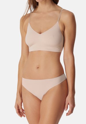 Bralette leggero, senza cuciture, di colore beige chiaro con spalline regolabili e design a scollo a V. Parte inferiore in stile bikini coordinata, con texture liscia.