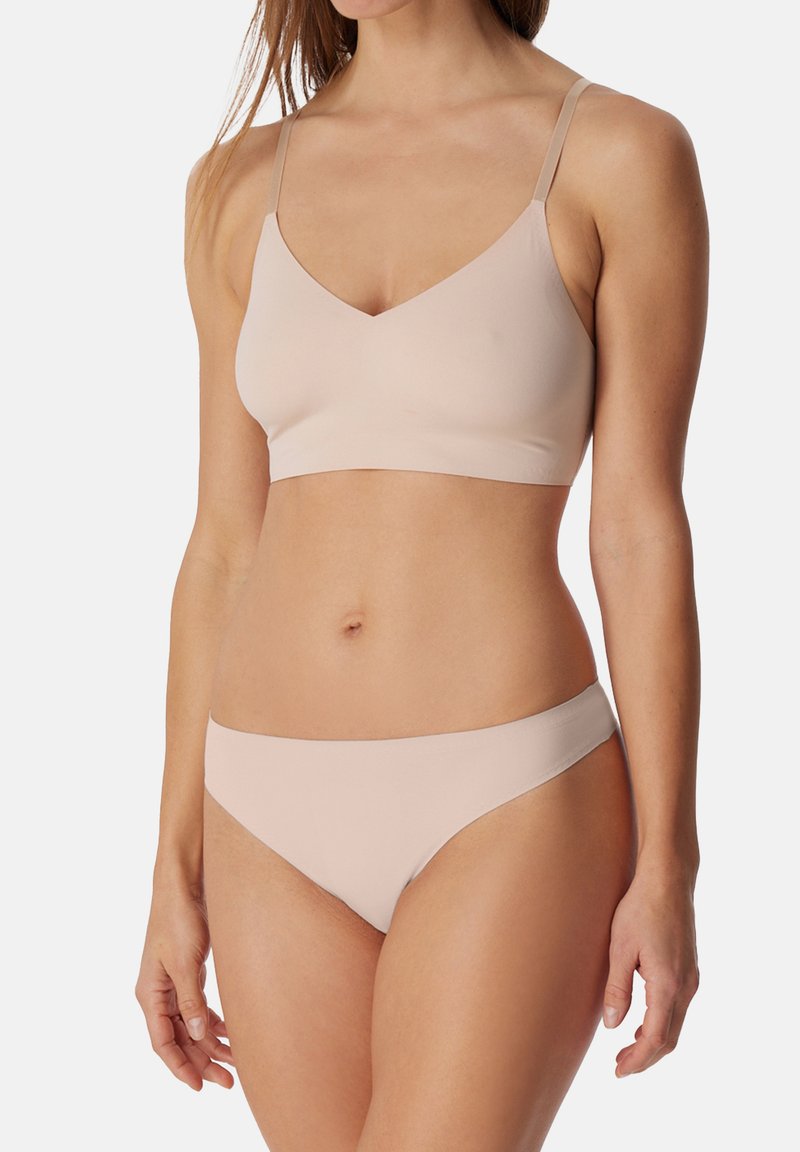 Kevyt, saumaton, vaalea beige bralette säädettävillä olkaimilla ja V-kaula-aukolla. Yhteensopiva bikinityyppinen alaosa, sileä rakenne.