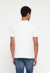 Tricou alb din bumbac, cu mâneci scurte, gât rotund și tiv drept. Dispune de o etichetă mică cu logo pe lateral. Design simplu și clasic.