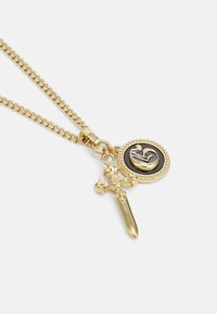 Gouden ketting met een dikke schakel, met een ronde hanger met een zwarte achtergrond en een verhoogd ontwerp, en een dolkcharme.