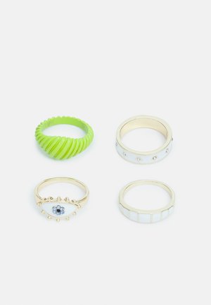 Quatro anéis: um em borracha verde em espiral; três de metal dourado, um com pedras azuis, um com pequenas gemas e um com detalhes brancos em grade.