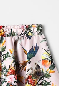 Růžová l�átka s květinovým a zvířecím vzorem, zahrnující opice a ptáky. Elastický pás s nařasením pro nastavitelné nošení.