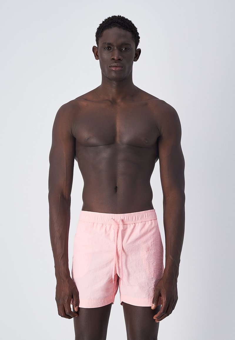 Costumi da bagno rosa chiaro con vita elastica e cordoncino. Il materiale è morbido, leggero e leggermente strutturato.