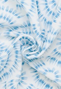Tessuto leggero con un motivo tie-dye blu su sfondo bianco, caratterizzato da forme vorticosi e una texture liscia.