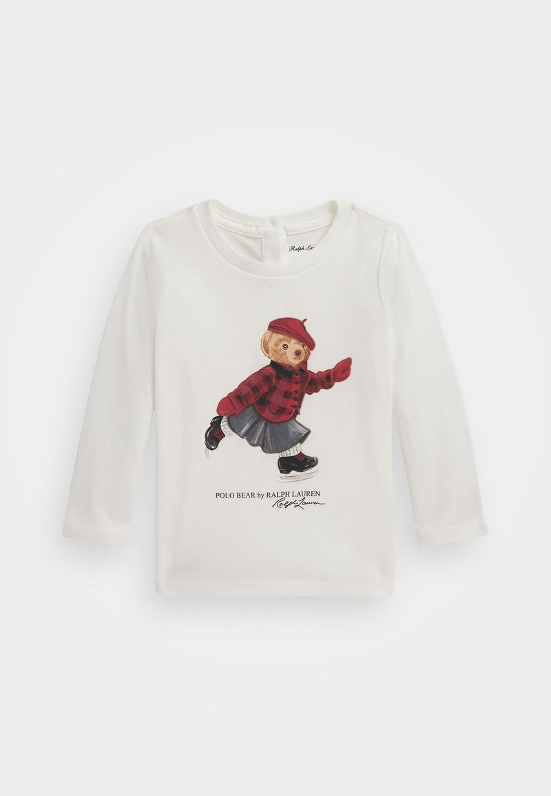 Balta garām piedurknēm t-kreklu, kurā redzams lācis sarkanas cekulainas krekla, denima svārku un melnu apavu apģērba grafika, ar tekstu "Polo Bear by Ralph Lauren".