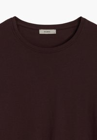 Bordowy bawełniany t-shirt z okrągłym dekoltem, krótkimi rękawami oraz metką z napisem "ATLANTIC" i rozmiarem "S" na wewnętrznej stronie kołnierza.