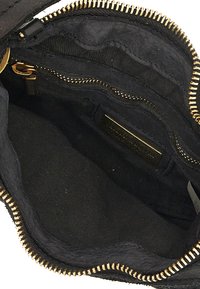 Interno di una borsa nera in tessuto con zip in metallo dorato. Presenta diverse tasche e un rivestimento testurizzato per l'organizzazione.