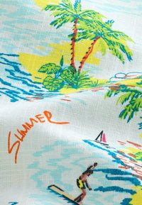 Tissu blanc avec une scène estivale colorée de plage comprenant des palmiers, des vagues et un surfeur, mise en valeur par un texte orange « Été ».