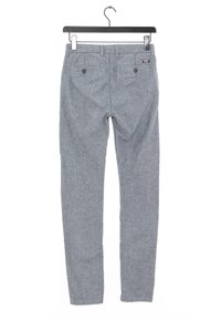 Pantaloni grigi intrecciati appesi a una gruccia nera. Presentano due tasche posteriori e un'etichetta in vita. La texture appare morbida e flessibile.