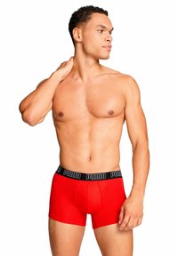Boxer rossi in cotone con una cintura elastica nera che riporta la scritta "PUMA". Il tessuto è liscio, presenta un design aderente e una tasca frontale.