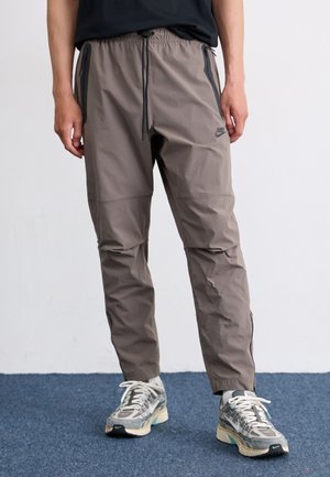 Nike joggers in gray fabric with an elastic waistband and drawstring. Features side zip pockets and a sleek, tapered design.