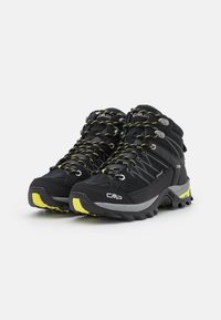 Botas de senderismo negras con acentos amarillos, hechas de material sintético texturizado. Incluyen características como una suela resistente y ojetes reforzados para los cordones.
