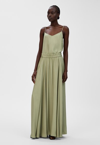Langes, fließendes Kleid aus leicht grünem Stoff mit satinierter Oberfläche. Verfügt über dünne Spaghettiträger und einen elastischen Bund für eine entspannte Passform.